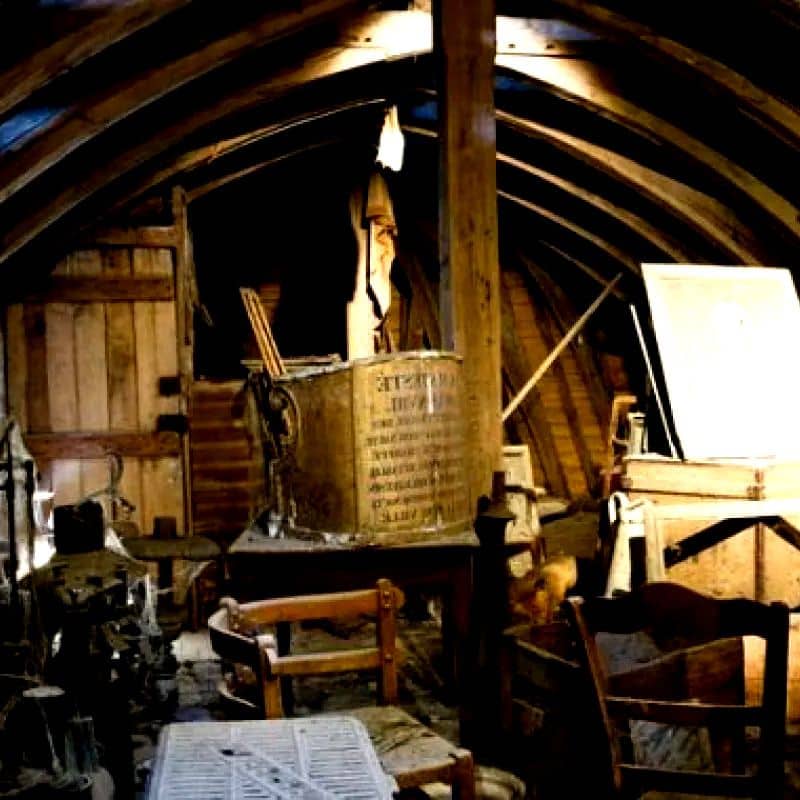 Grenier sous charpente rempli de meubles anciens et de malles