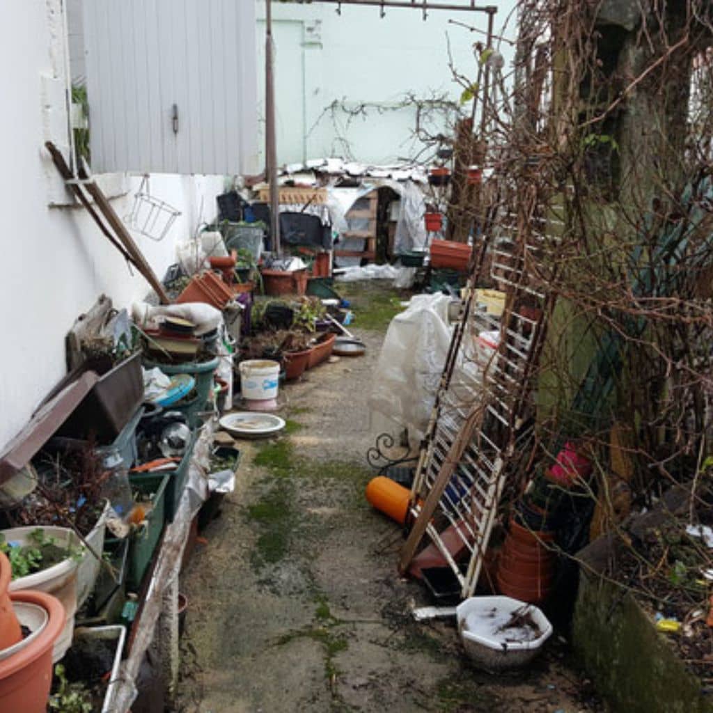Cour et jardin encombrés d’objets et de déchets avant débarras